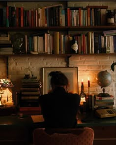 a woman sitting at a desk in front of a book shelf filled with books