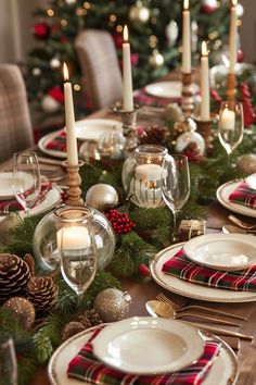 a table set for christmas dinner with candles and plaid napkins on the place setting