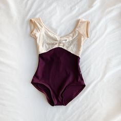 a purple and white one piece swimsuit laying on top of a bed