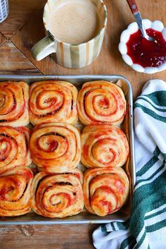 a pan filled with cinnamon rolls next to a cup of coffee