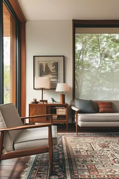 a living room filled with furniture next to large windows and a rug on the floor