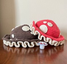 two crocheted hats sitting on top of a wooden table