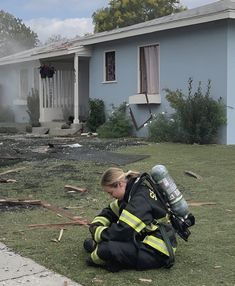 a firefighter kneeling on the ground in front of a house