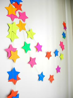 colorful paper stars are hanging on the wall