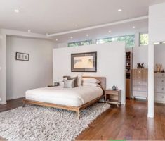 a bedroom with hardwood floors and white walls, along with a large bed in the center