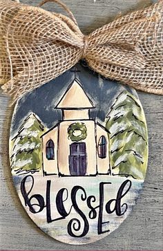 a painted ornament with the word, blessing on it and a church in the background