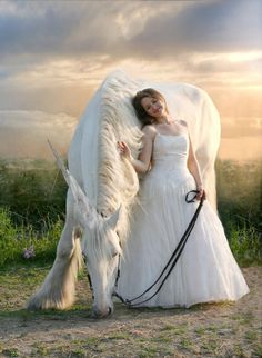 a woman in a white dress is standing next to a horse with long manes