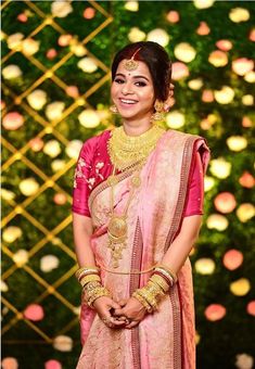 a woman in a pink and gold sari smiles at the camera while posing for a photo