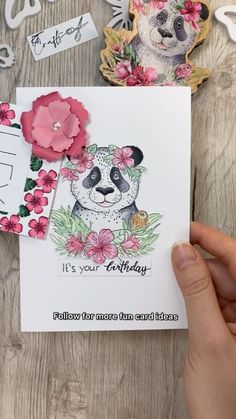 someone holding up a card with a panda bear on it and flowers around the edges