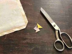 a pair of scissors sitting on top of a wooden table next to some pieces of paper