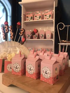 pink and white candy boxes with numbers on them are sitting on a wooden table in front of a shelf