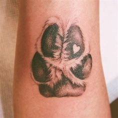 a tattoo on the arm of a person with a dog paw and heart in it