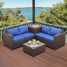 an outdoor patio furniture set with blue cushions on a wooden deck overlooking the water and trees