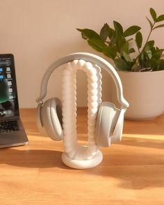 a laptop computer sitting on top of a wooden desk next to headphones and a plant