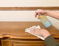 a woman cleaning a wooden dresser with a rag