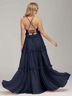 the back of a woman wearing a dark blue dress with straps and tiered ruffles