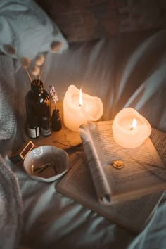 an open book and two lit candles on a bed