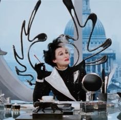 a woman sitting at a desk in front of an artistic sculpture with spoons and utensils