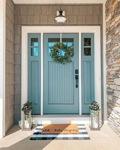 a blue front door with two wreaths on it and a black and white checkered rug