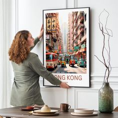 a woman standing in front of a large poster with the words hong kong on it