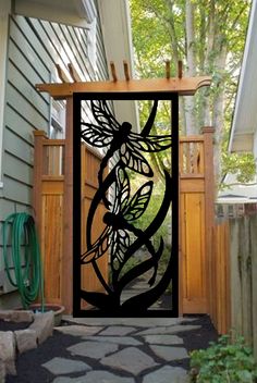 an iron gate with a dragon design on the side of a house in front of a tree