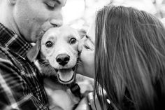 a man and woman kissing their dog in black and white with trees in the background