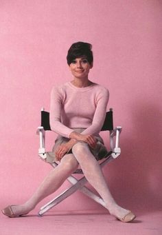 a woman is sitting in a chair with her legs crossed and wearing white tights