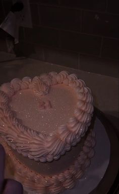 a heart shaped cake sitting on top of a white plate next to a person's hand