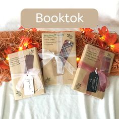 three books are wrapped in brown paper and tied up with ribbon, sitting on a bed