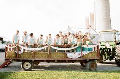 a large group of people riding on the back of a hay wagon in front of a grain silo