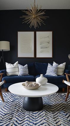 a living room with blue couches and white coffee table in front of two pictures on the wall