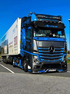 a blue and black semi truck driving down the road