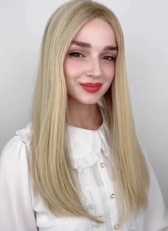 a woman with long blonde hair wearing a white shirt and red lipstick is posing for the camera