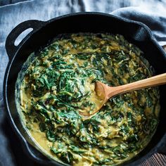 spinach and cheese sauce in a skillet with a wooden spoon on the side