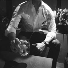 a man sitting at a table with a glass in front of him and his hand on the bowl