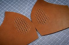 two pieces of brown leather with holes on them