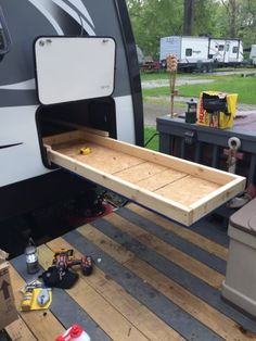 a camper with the door open and some tools on the ground