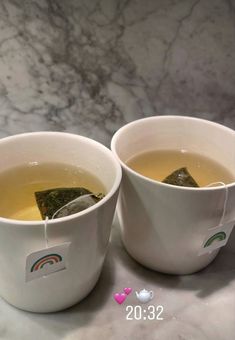 two white bowls filled with green tea on top of a table