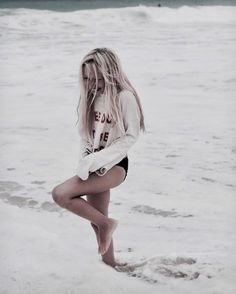 a woman is standing in the water at the beach