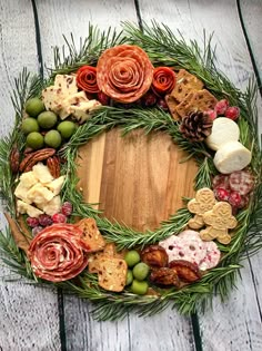 a wreath made out of different types of food on a wooden table with pine cones and berries