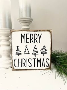 a merry christmas sign sitting on top of a table next to two white candle holders