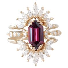 a ring with a large red stone surrounded by white and gold diamonds on top of it