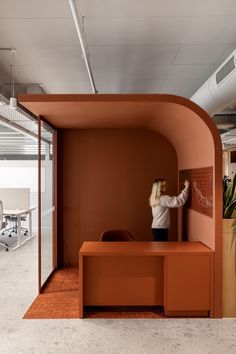 a woman is writing on the wall next to a desk in an open office space