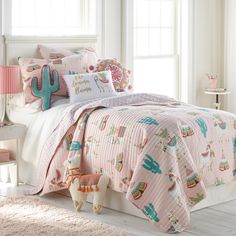 a bedroom with pink and white bedding, cactus pillows, and a stuffed animal