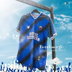 a soccer jersey is hanging on a wooden pole in front of blue sky and clouds