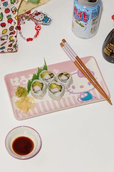 sushi on a plate with chopsticks next to an empty cup and sauce