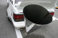 the back end of a white car parked in a parking lot next to a traffic light