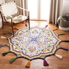 a colorful rug with tassels on the floor next to a chair and window