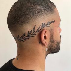 a man with a tattoo on his forehead and behind the ear is a fern leaf