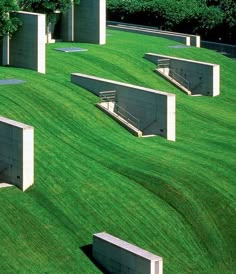 several concrete benches sitting on top of a lush green field